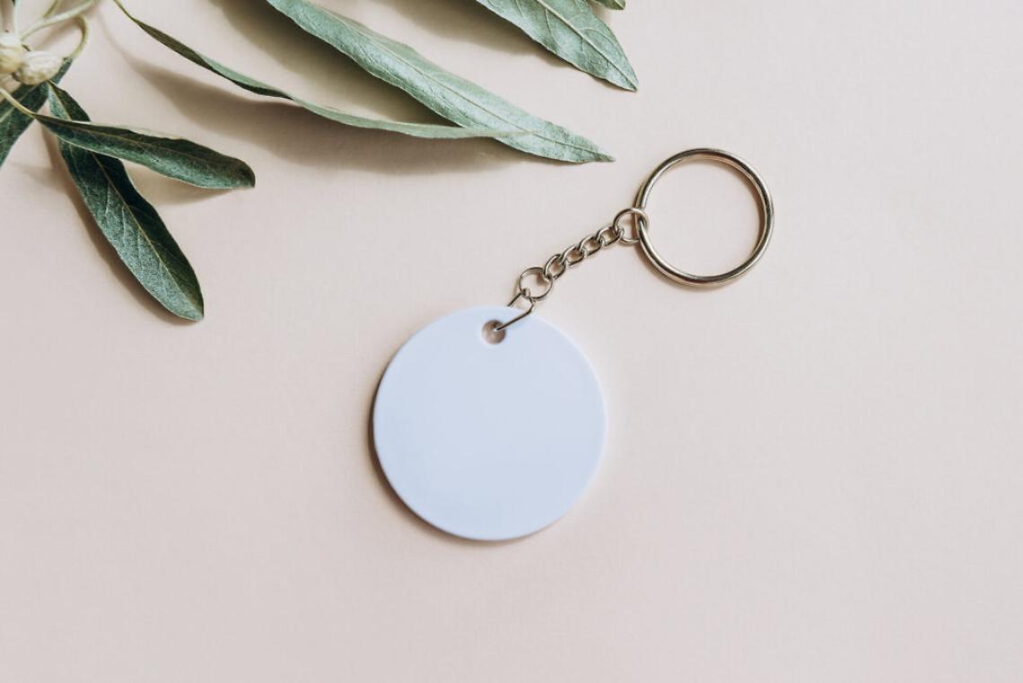 Keychain mockup among olive leaves to display design Blank white sublimation key chain photo