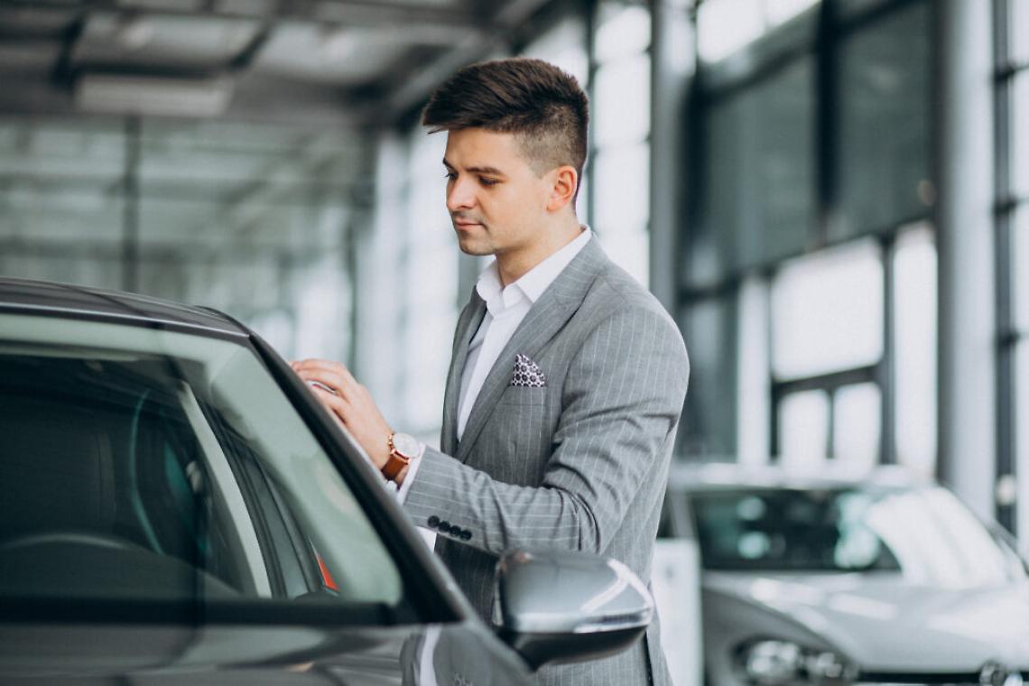 Young handsome business man choosing a car in a car showroom