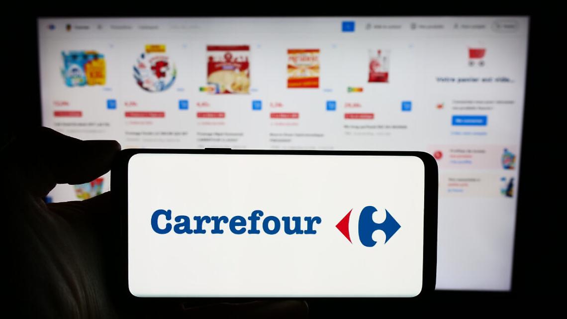 Stuttgart, Germany : Person holding cellphone with logo of French retail company Carrefour SA in front of business webpage Focus on phone display