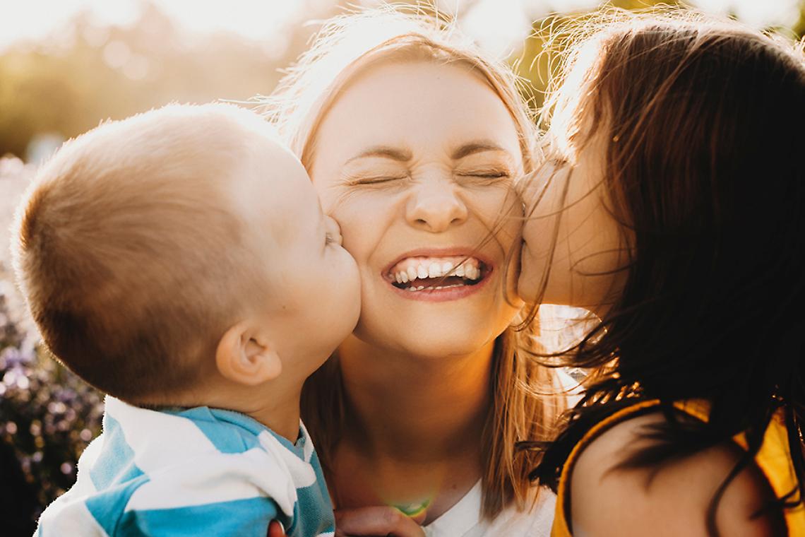 Close up portrait of lovely young mother laughing with closed ey