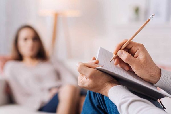 Pay attention to details. Selectife focus of pencil in hands of professional psychotherapist holding it and making notes while talkign with his client