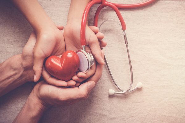 child and adult holding red heart with stethoscope, heart health,  health insurance concept