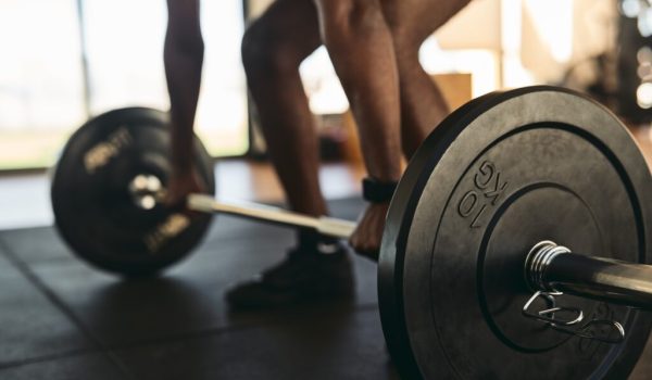 Strong sportsman doing exercises with barbell