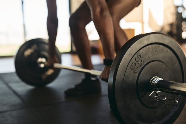 Strong sportsman doing exercises with barbell