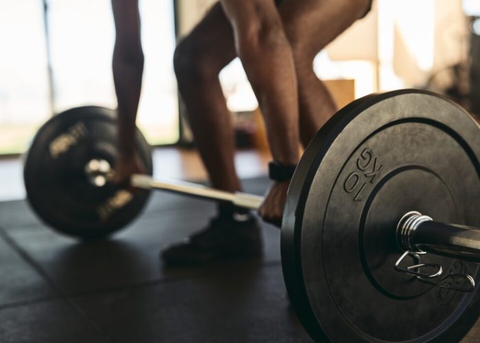 Strong sportsman doing exercises with barbell