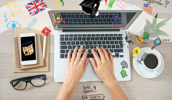 Young woman with laptop studying English online, top view