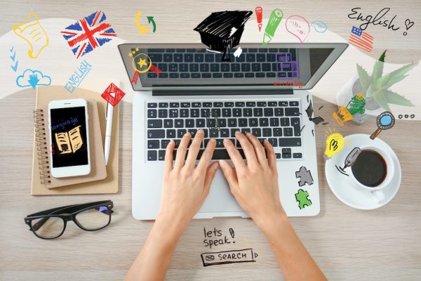 Young woman with laptop studying English online, top view