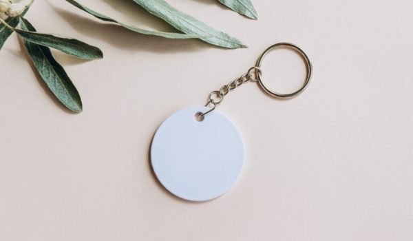 Keychain mockup among olive leaves to display design Blank white sublimation key chain photo