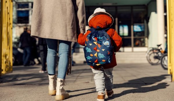 A mother entering the kindergarten yard with her preschooler boy