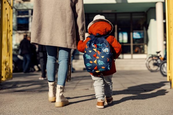 A mother entering the kindergarten yard with her preschooler boy