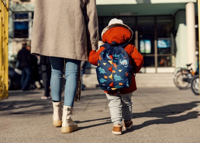 A mother entering the kindergarten yard with her preschooler boy