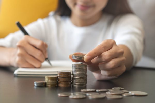 Financial, asian young woman, girl putting stack coins on table for calculate cost sitting in living room at home, financial plans to spend enough money on his income for saving money and payment