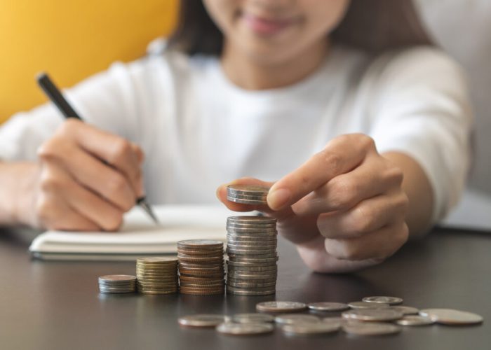 Financial, asian young woman, girl putting stack coins on table for calculate cost sitting in living room at home, financial plans to spend enough money on his income for saving money and payment