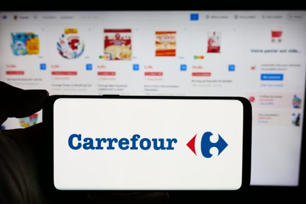 Stuttgart, Germany : Person holding cellphone with logo of French retail company Carrefour SA in front of business webpage Focus on phone display