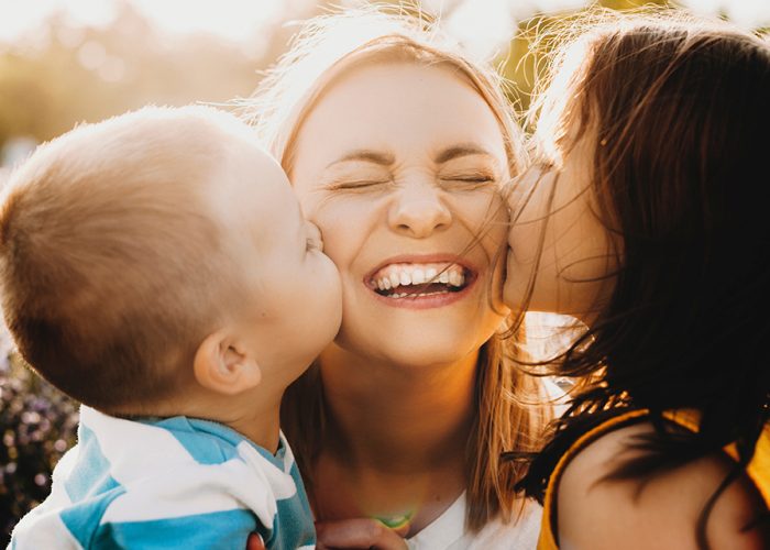 Close up portrait of lovely young mother laughing with closed ey