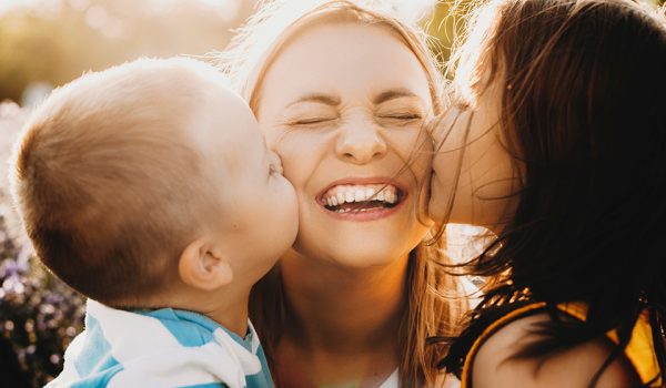 Close up portrait of lovely young mother laughing with closed ey