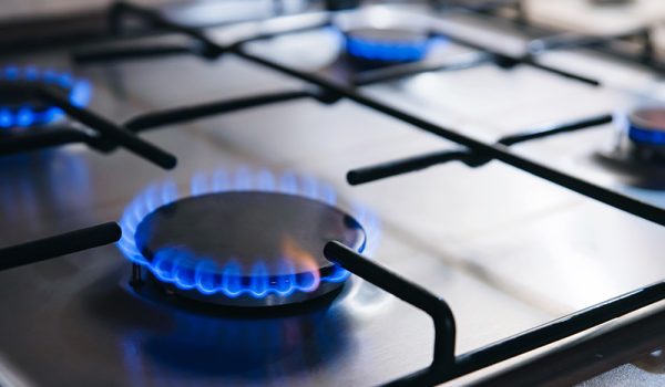 Gas kitchen stove cook with blue flames burning. Panel from steel with a gas
