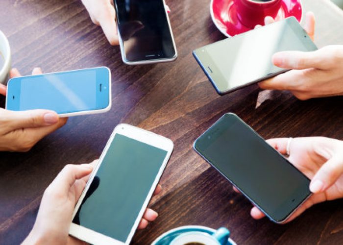 Friends at table with circle of smartphones