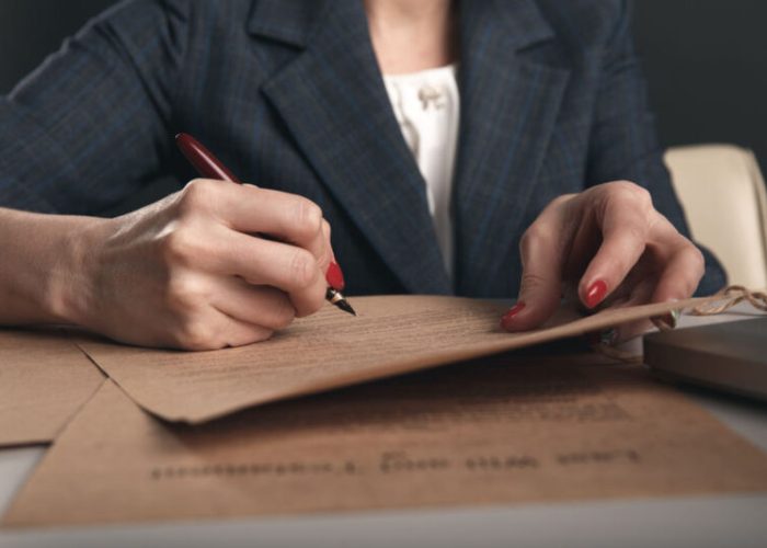 Closeup view of woman attorney writing on documents by pen