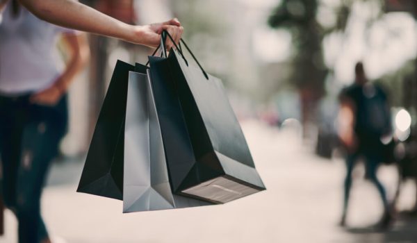 Close up of woman`s hand holding shopping bags while walking on the street.