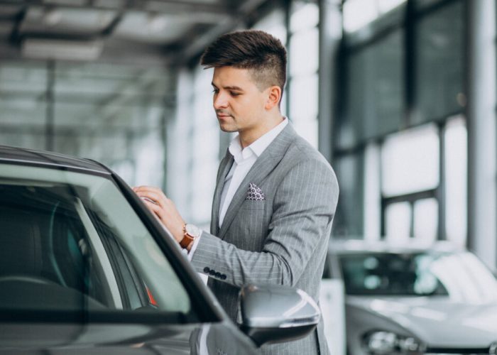 Young handsome business man choosing a car in a car showroom