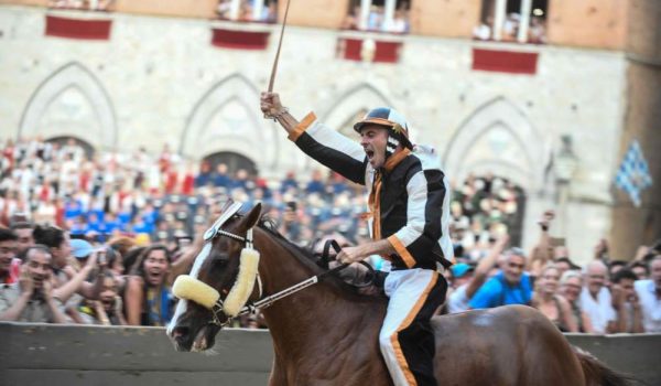 Jockey of the the contrada "Lupa" Giuseppe Zedde, known as "Gingillo", rides his horse Portgo Alabe as they compete and win the historical Italian horse race Palio di Siena , on August 16, 2018, in Siena. (Photo by Carlo BRESSAN / AFP)